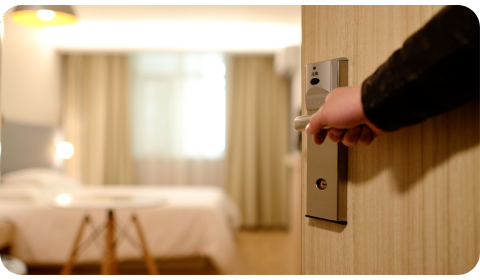 Photo of a hand opening a hotel room. You can see the bedroom in the background.